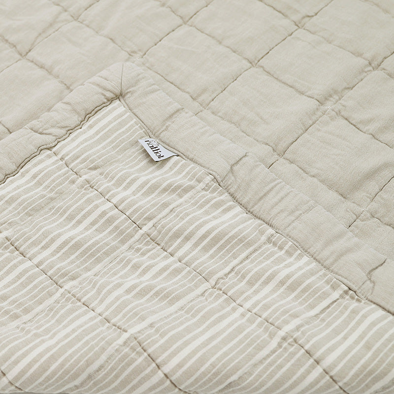 Anna is reversible: one side is plain and the other is striped, both with a quilted effect. Its subtle color, a sand complexion patinated by a stone wash which makes the cotton even softer.