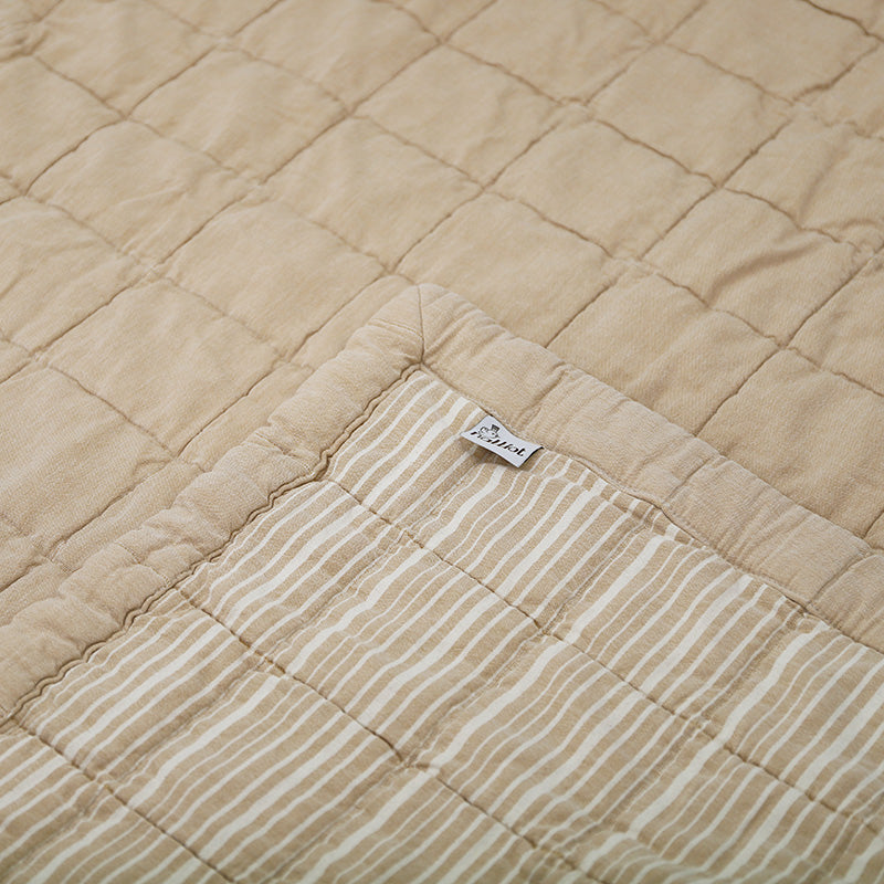 Anna is reversible: one side is plain and the other is striped, both with a quilted effect. Its subtle color, a caramel complexion patinated by a stone wash which makes the cotton even softer.